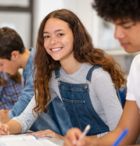 A teen with clear skin smiles amongst her classmates