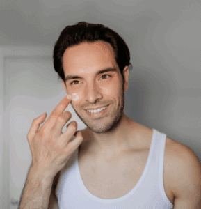 A man applies skin care in the mirror